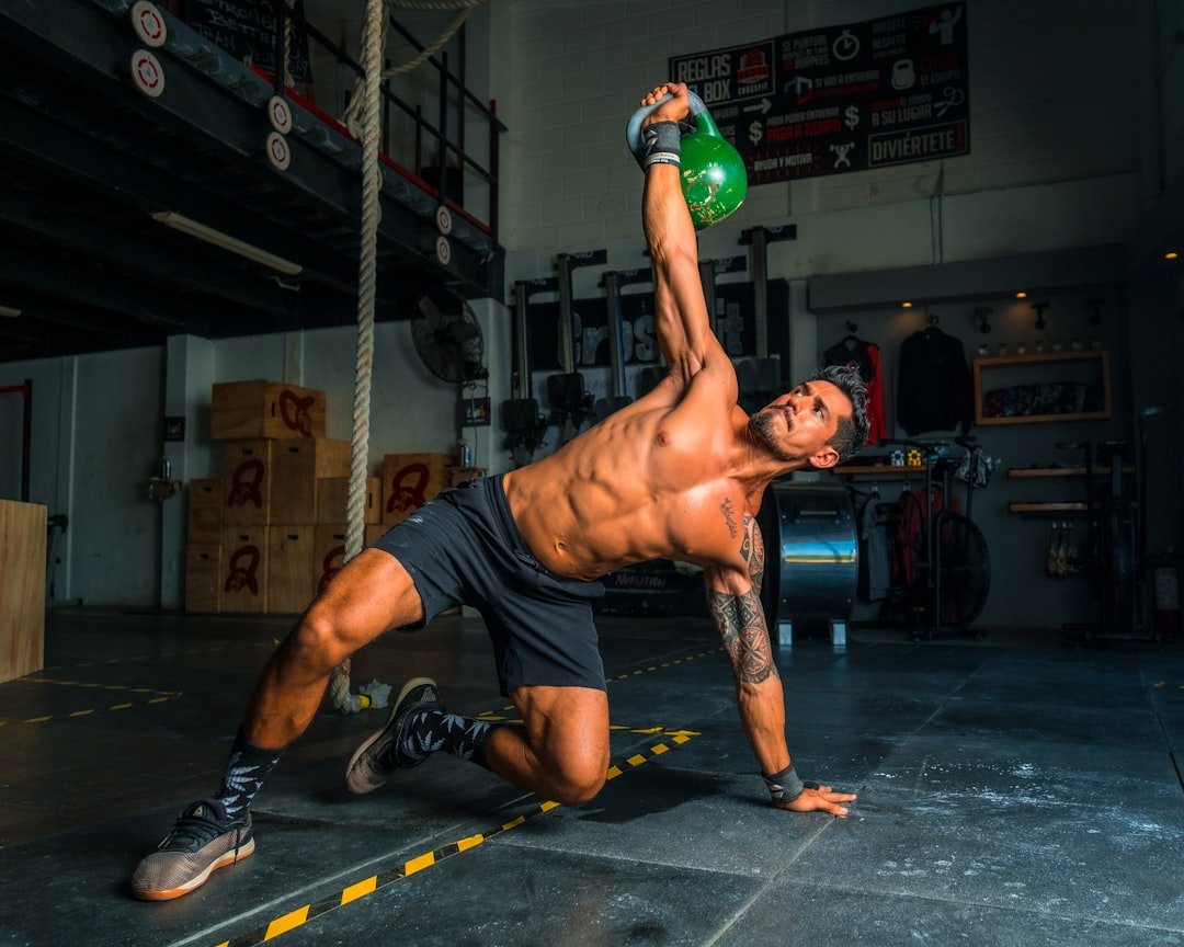 A person stretching or relaxing after a workout, surrounded by fitness equipment and a water bottle.